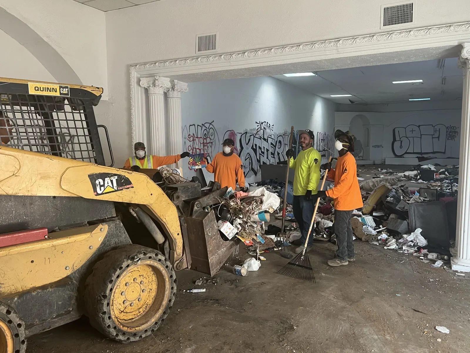 Crew and skid steer clearing debris out of a gutted commercial interior